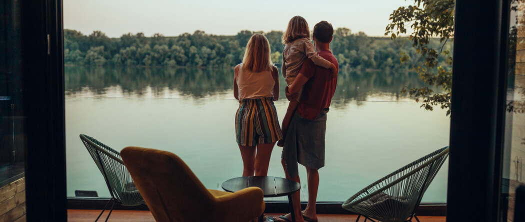 Family of three standing on deck overlooking lake