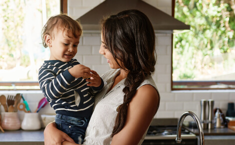 A mother holding her child in a kitchen
