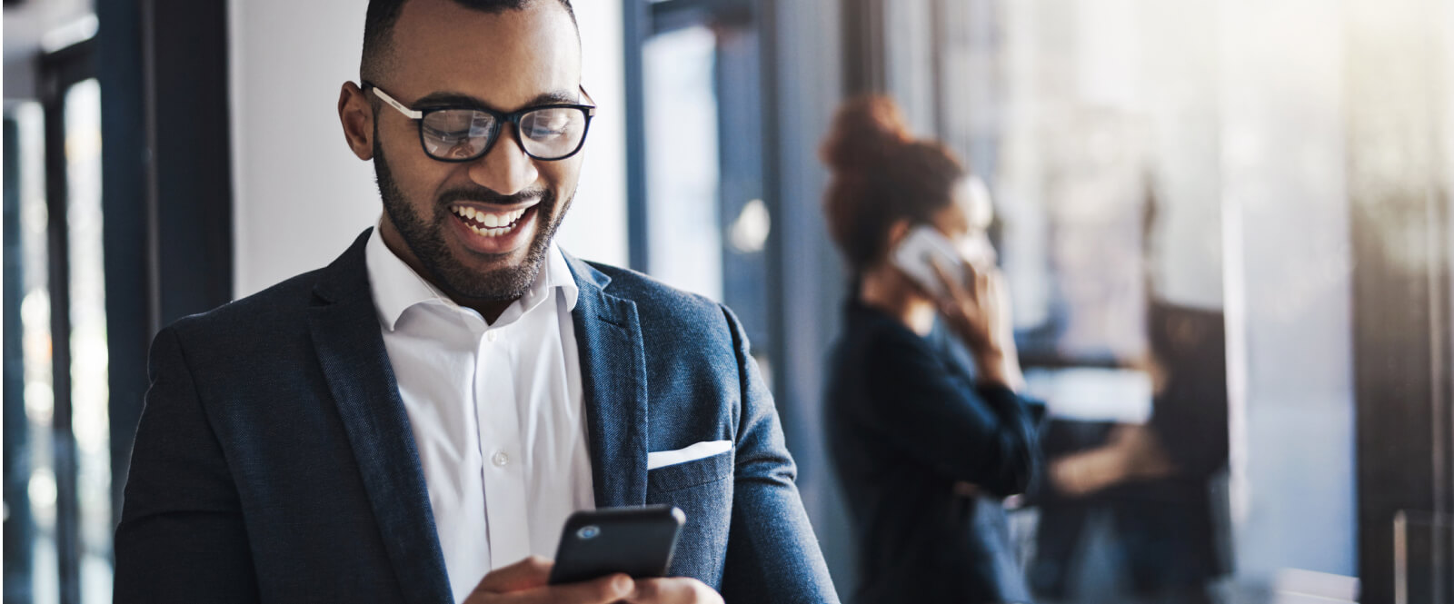 Young businessman smiling while looking at a mobile phone.