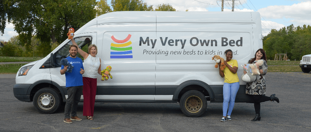 Four people smiling in front of van