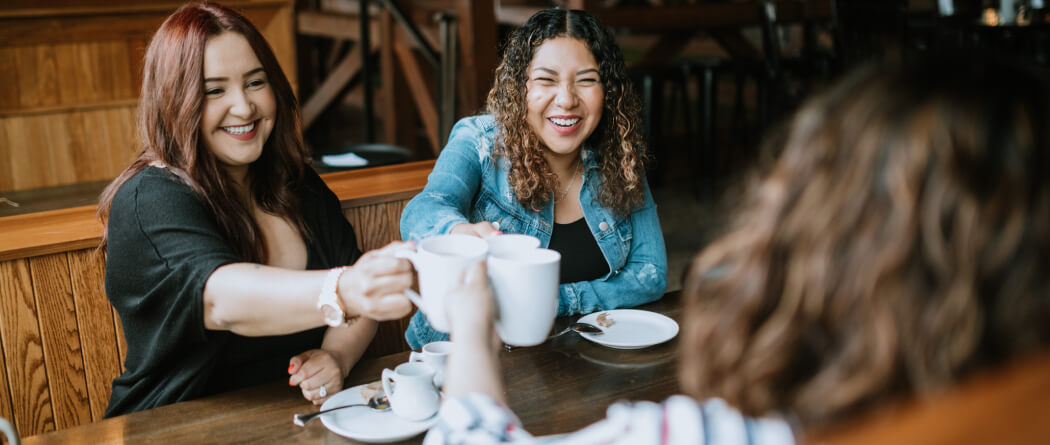 Three friends clinking coffee mugs