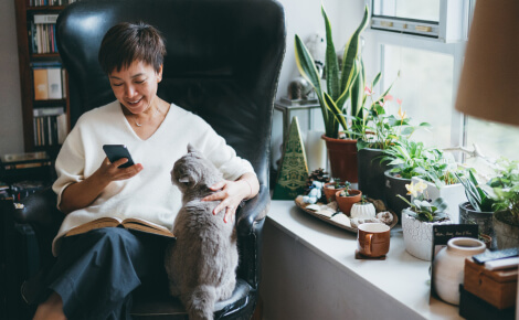 Woman using mobile chair and petting cat in living room