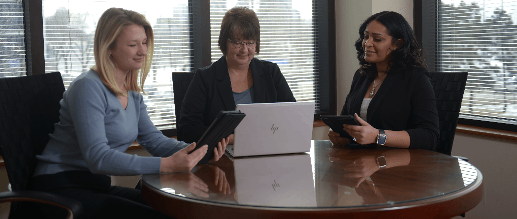 Three women looking at laptop and tablets