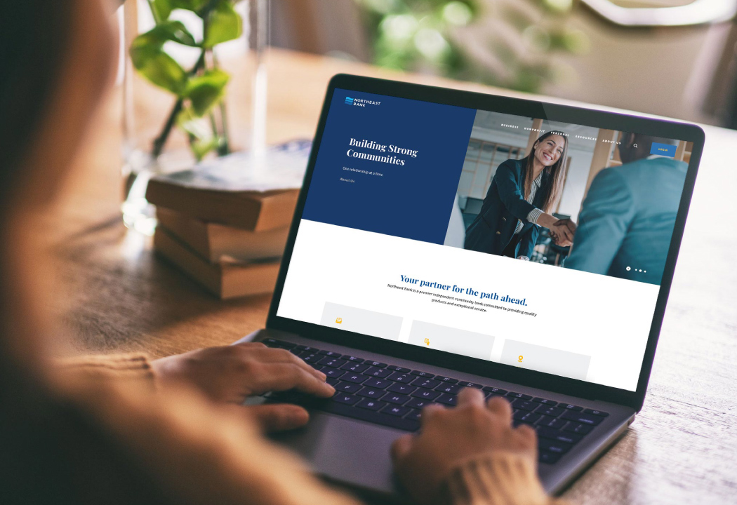 Woman visiting Northeast Bank website on laptop at a desk